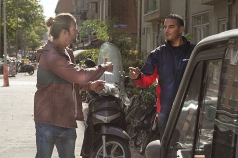 Twee mannen staan bij scooter. Een steekt zijn duim omhoog. 