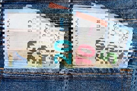 Briefjes geld in een broekzak. 