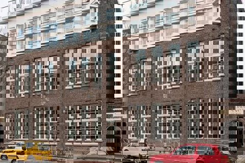 Gevel met rode en gele auto ervoor. 