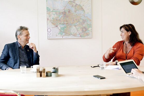 Twee mensen zitten in een vergadering. 