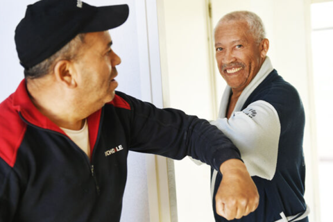 Ellebogen tegen elkaar aan in Corona tijd. 