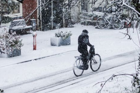 Fietser in besneeuwde straat.