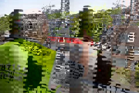 Man steekt duim op vanaf balkon.