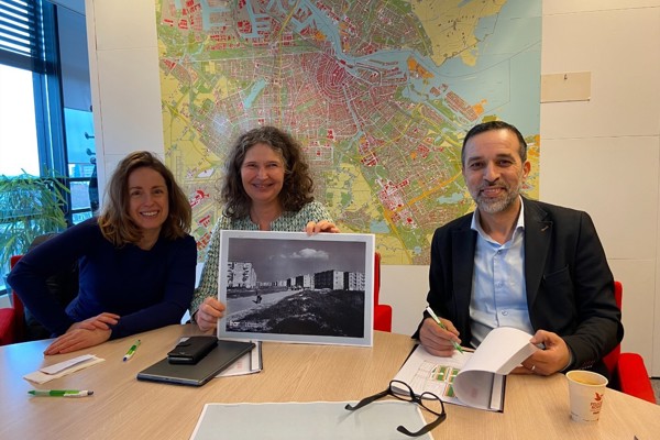 Foto van drie mensen aan tafel trots kijkend bij het tekenen van overeenkomst