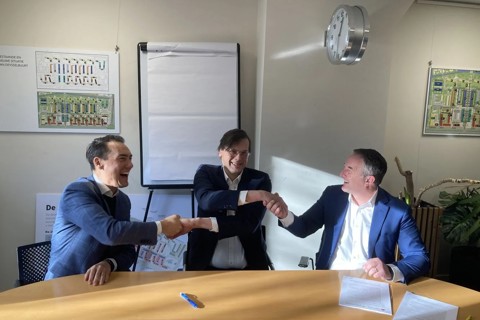 drie mannen schudden elkaar de hand aan tafel