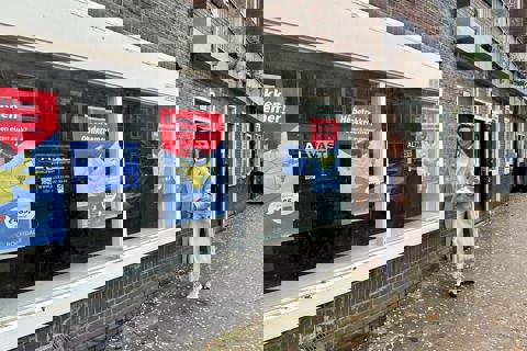 Foto van een lachende vrouw voor een pand dat te huur is voor ondernemers