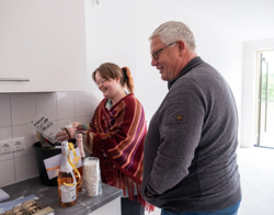 Twee bewoners in keuken met welkomstpakket en champagne