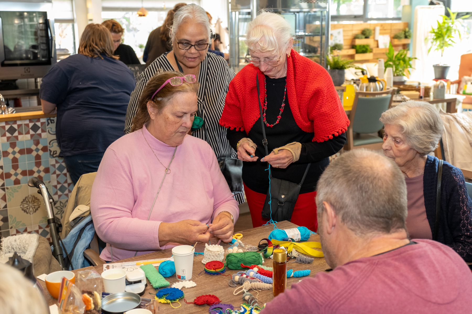 Een groep ouderen staan en zit rondom een tafel, bezig met knutselen